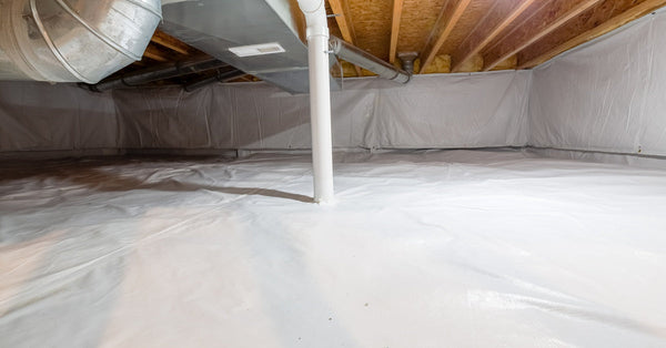 A white vapor barrier covers the floors and walls of an encapsulated basement crawlspace with a light on the ceiling.