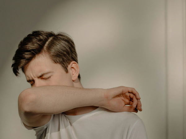 A man in a white shirt is feeling sick