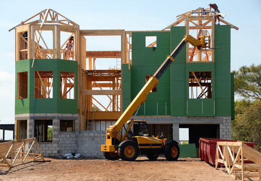 Yellow and black heavy equipment near an unfinished building.