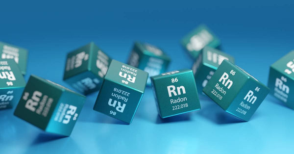 A group of 11 dice that all have the chemical symbol and number for radon, rolling on a blue surface.