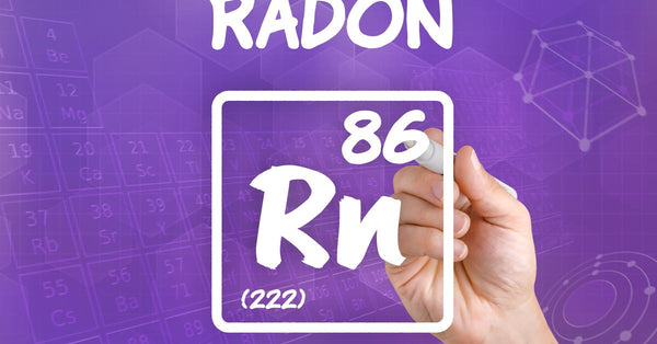 A hand holds a white marker and writes the atomic information for "Radon 86 Rn 222" on a purple background.