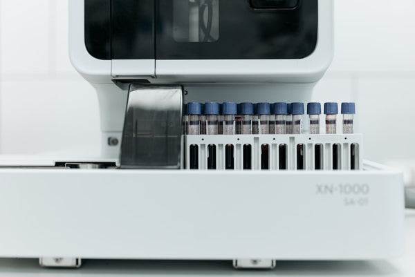 Close-up of an XN-1000 laboratory analyzer with rows of sample tubes, representing scientific testing.